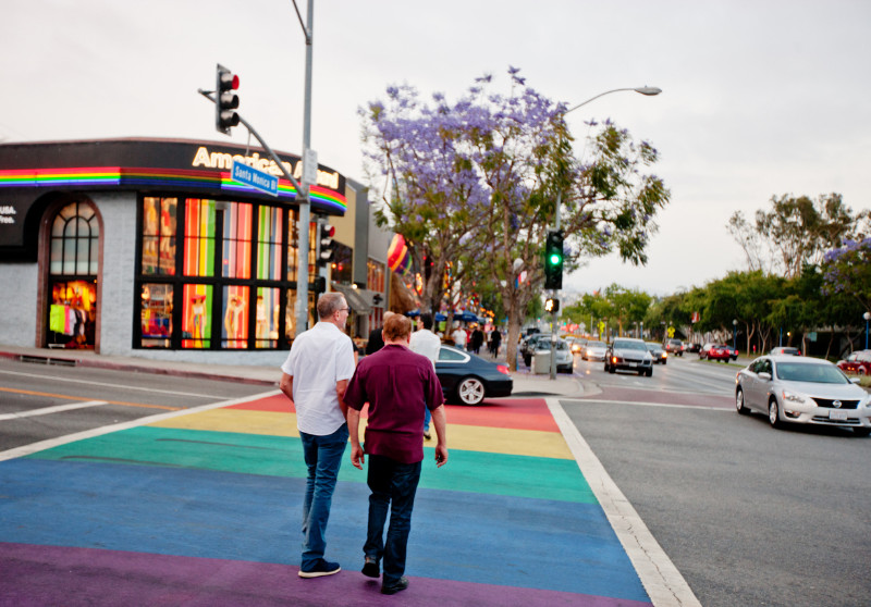 Two men crossing the rainbow colored pedestrian lane